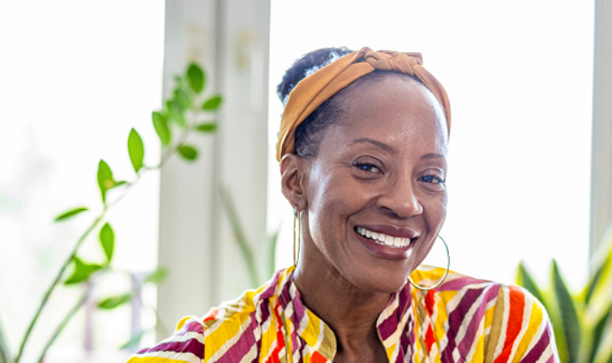 Smiling older woman in a striped shirt and headscarf sitting at a laptop