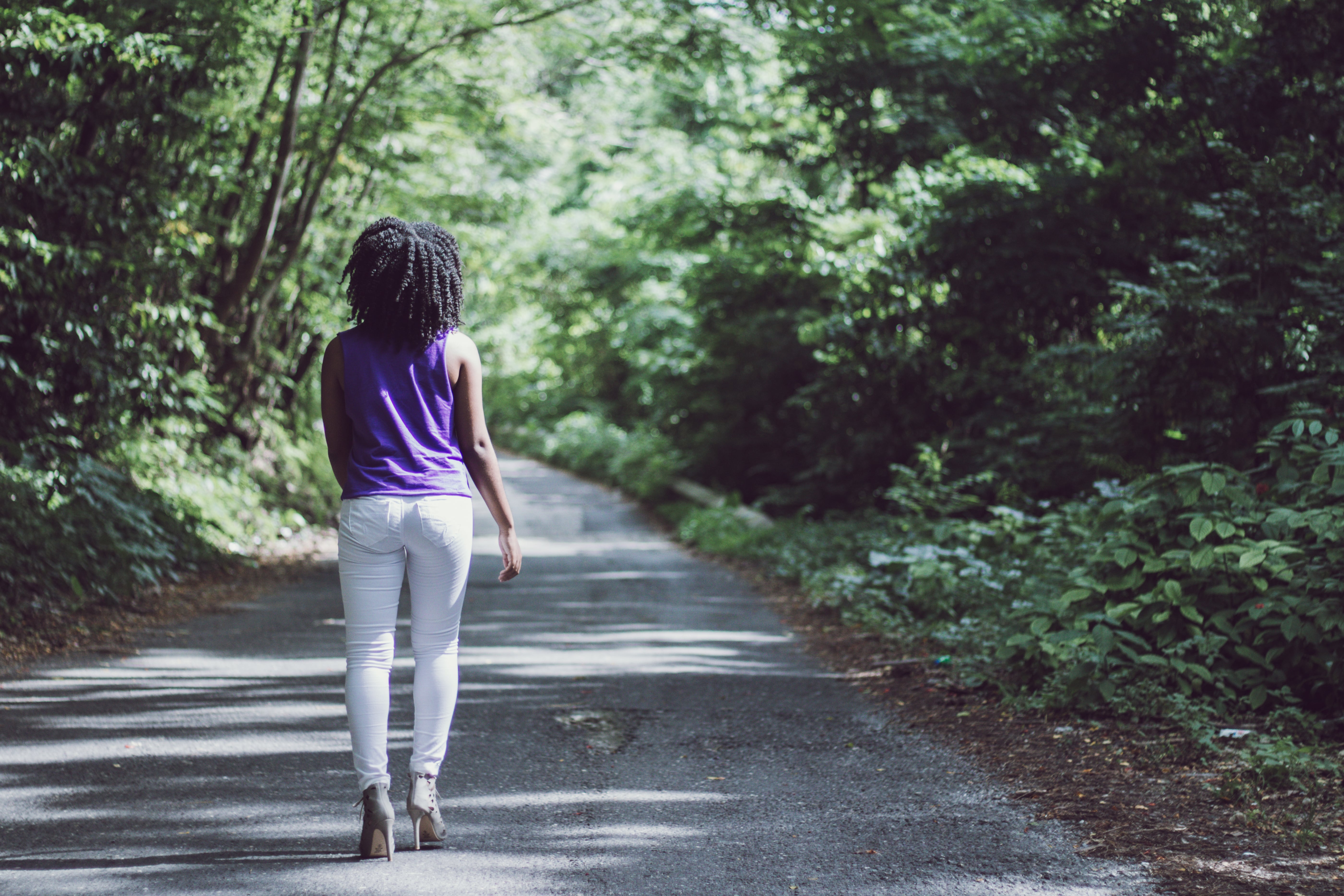woman-in-heels-walking-on-concrete-road-surrounded-with-tall-2953581