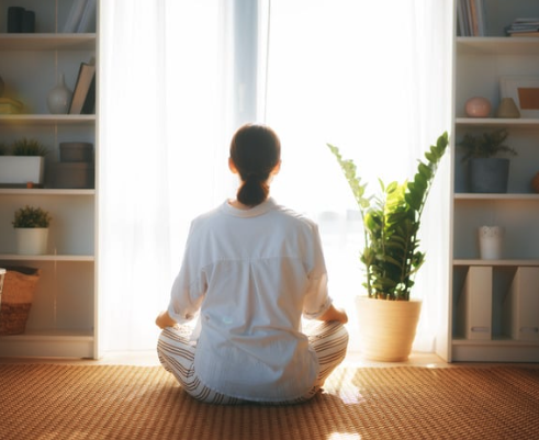 A woman faces a window and meditates