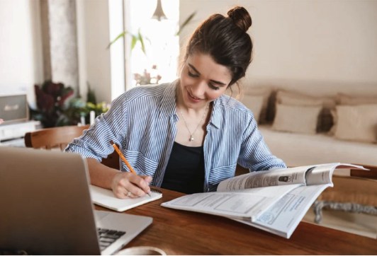 A woman studies at a desk with a laptop
