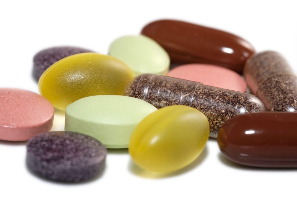 close up shot of a number of pills in different shapes and sizes in colors brown, yellow, red and green