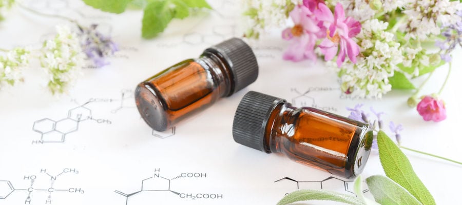 two brown bottles lie on a table surrounded by small pink and white flowers