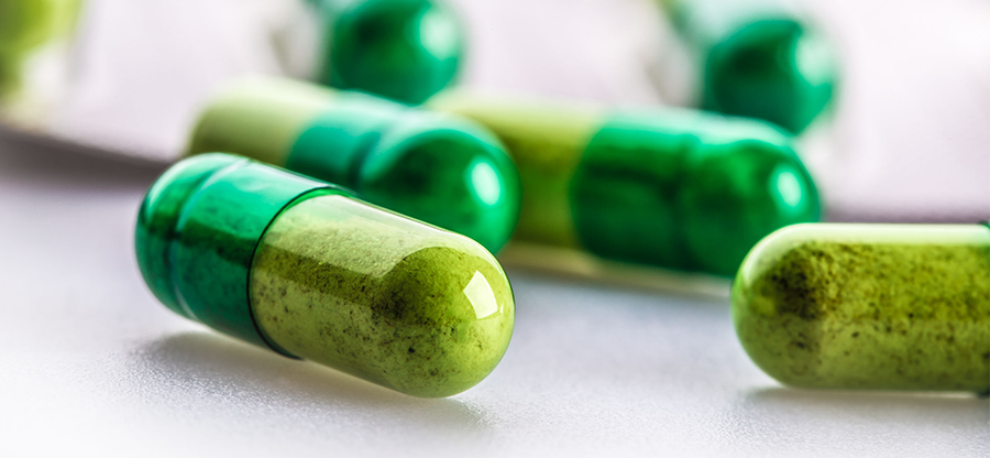 close up shot of pills that are half light green, half dark green with powder inside of them