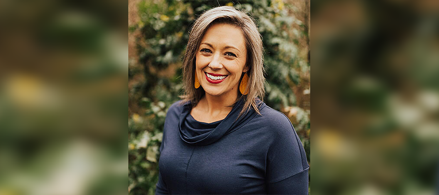 woman with short brown hair wearing a dark blue shirt smiles at the camera