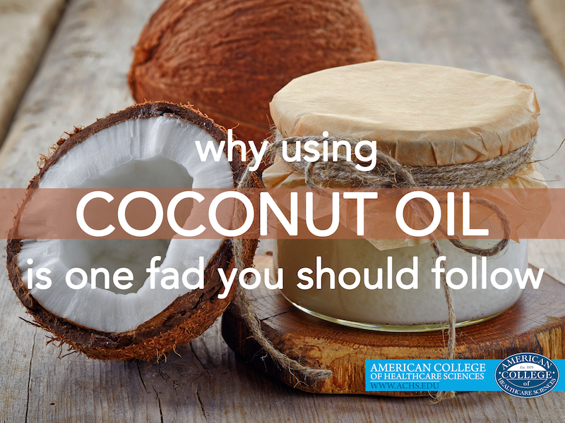 a coconut cracked open leans against a jar of coconut oil on a wooden tabletop. copy overlaid on top of image says "why using coconut oil is one fad you should follow"