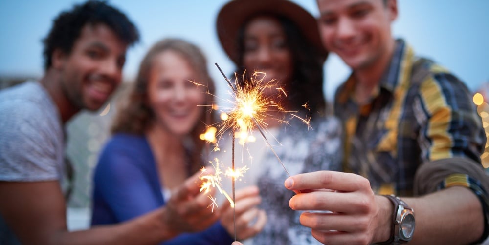 four people hold lit sparklers to the foreground of the camera