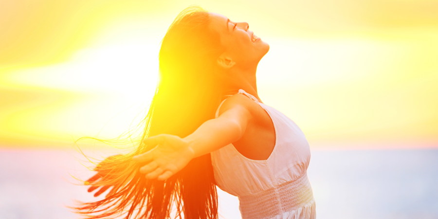 a woman with long dark hair wearing white smiles with her face tilted up, hands out to her side