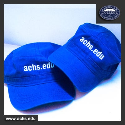 bright blue hats that say achsedudev.wpenginepowered.com on them sit on a white table with a white background