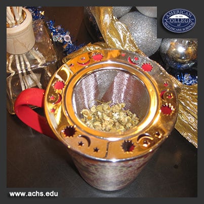 dry camomile tea sits in a tea strainer, ready for hot water to be poured over it into the cup below