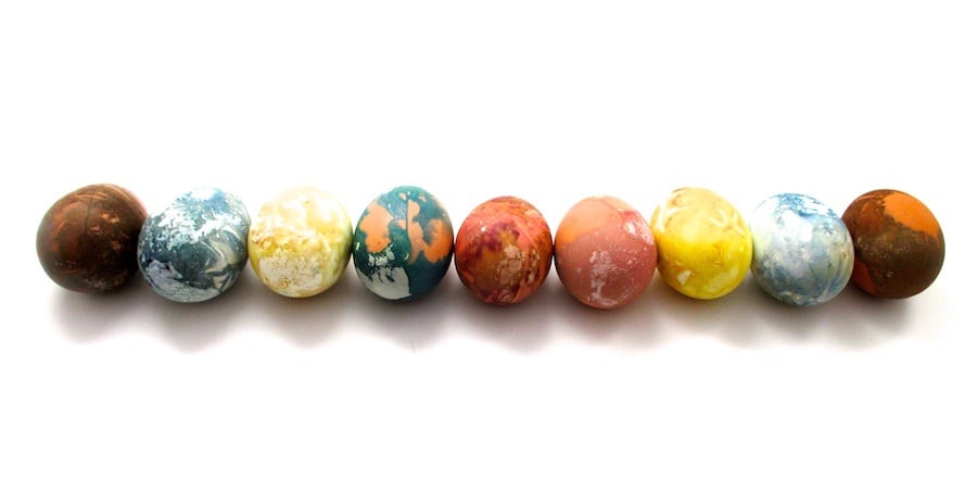 eggs dyed in a tie-dye way are laid out in a row on a white background