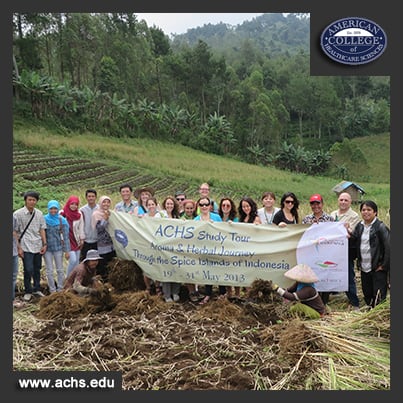 a group of people hold a fabric sign in a field in indonesia celebrating a ACHS study tour