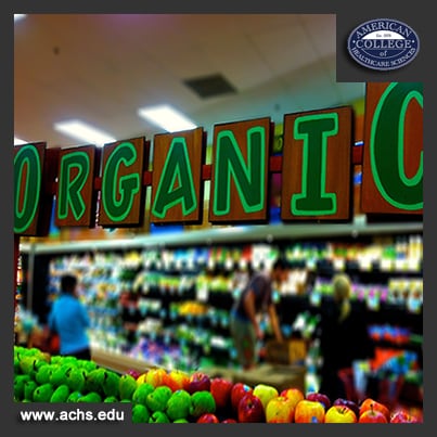 the word organic is written in large green letters and hung over a selection of fruit in a grocery store