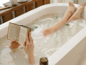 A woman reads. a book while soaking in an herbal bath