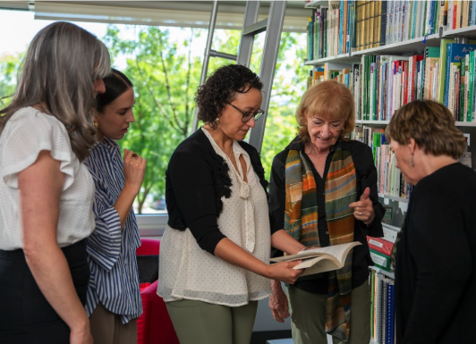 ACHS faculty look at a book in the library