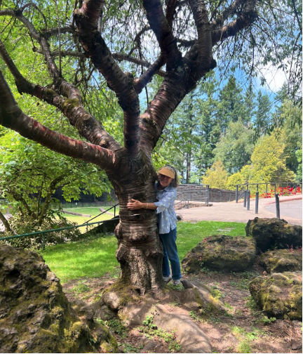 A woman hugs a large tree in Mt. Tabor Park