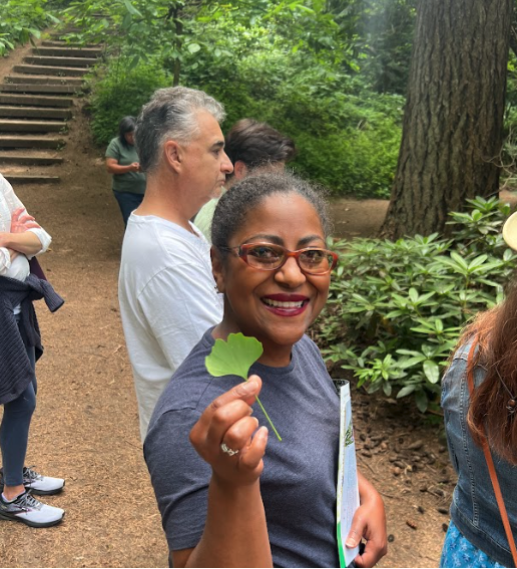 A woman holds up a leaf and smiles