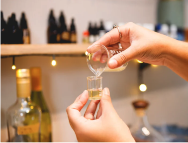 pouring essential oil from a beaker into a smaller beaker