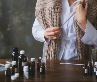 A person standing next to a table with an assortment of essential oils