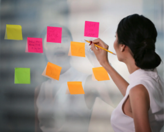 A woman sticks colorful post-its to a glass window