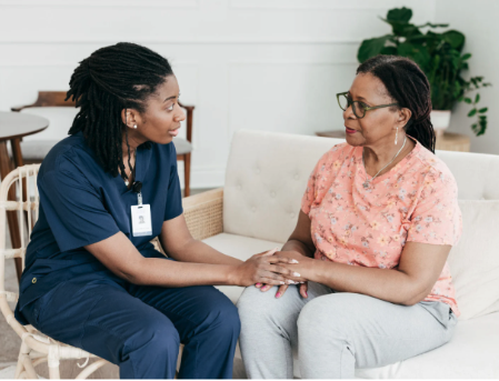 A healthcare worker and client sit and hold hands