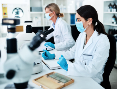 Two women with face masks work in a science lab