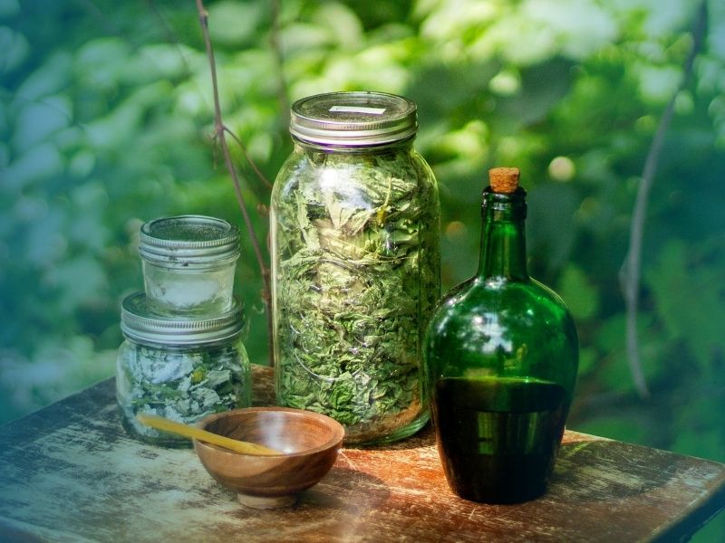 Jars of dried herbs and a green bottle on an outdoor table