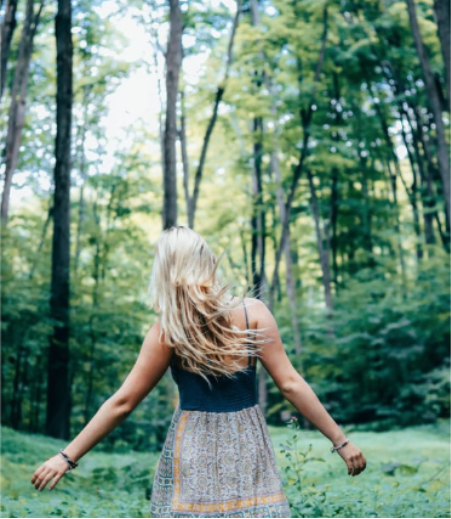 A woman in a dress walks through a green forest