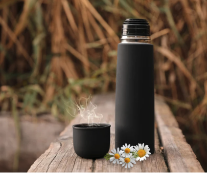 a thermos of hot tea with chamomile flowers