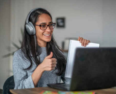 A woman wearing headphones and working on a laptpo