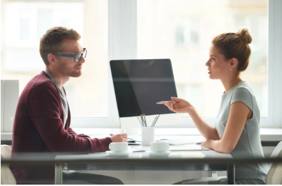 A man and a woman sitting at a desk in an office
