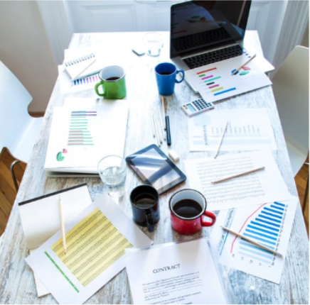 A messy work desk with a laptop and papers