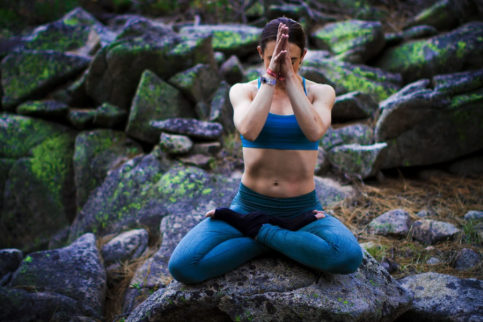 A woman sitting outside cross-legged in a yoga pose