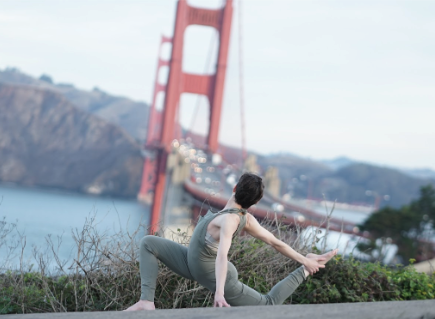 A woman doing a yoga pose in front of the Golden Gate bridge