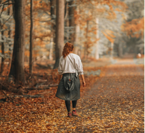 A woman walking ion a path in the woods in autumn