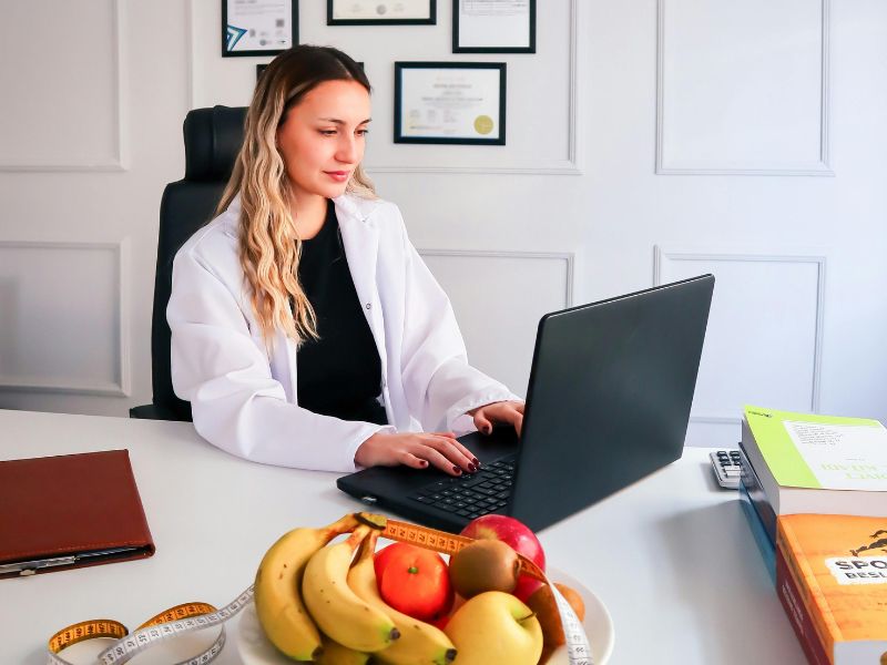 A wellness professional working at a desk with a laptop