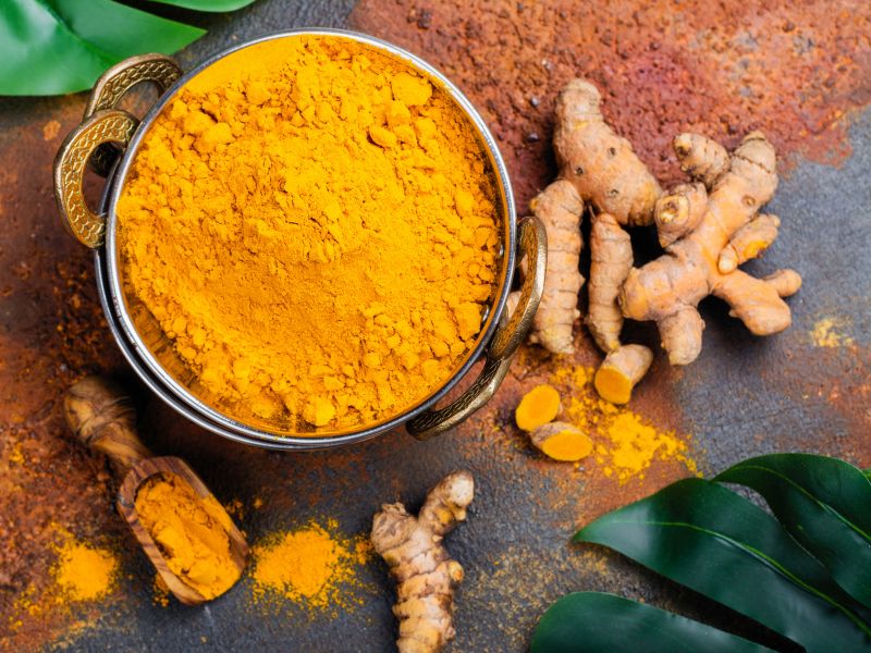 Turmeric root and powdered turmeric in a bowl