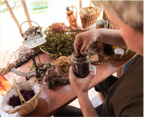 An herbalist putting dried herbs in a glass container