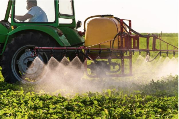 A tractor spraying pesticides on plants