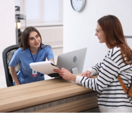 Clinic worker helping a patient at a reception desk