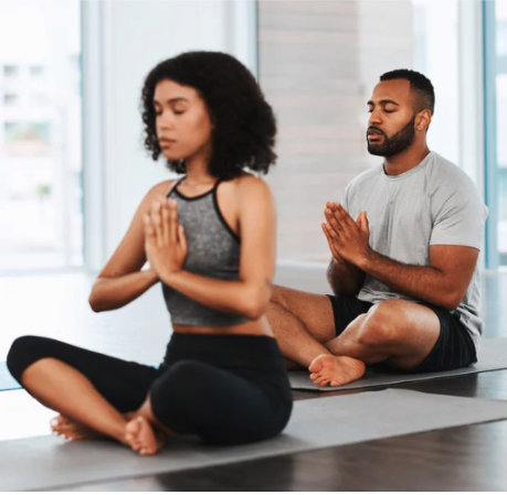 Two people sitting cross legged in a yoga pose