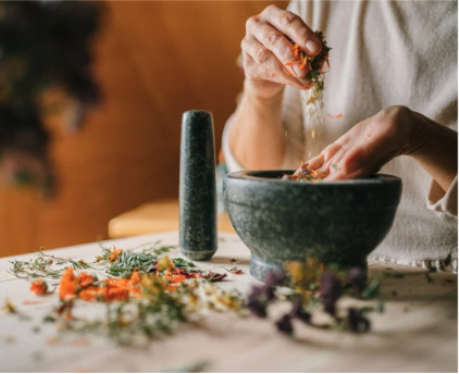A person working with herbs and a crucible