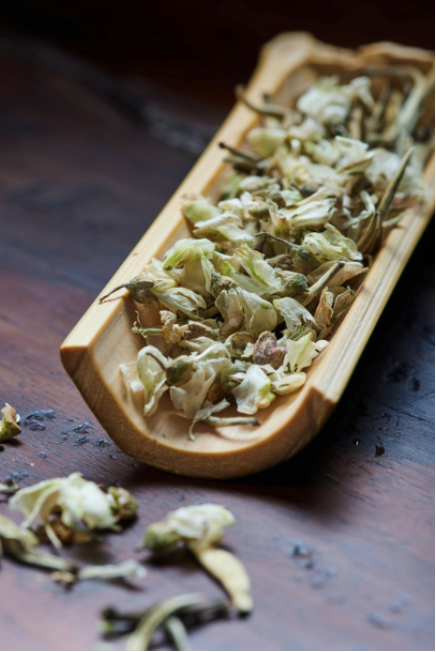 a wooden scoop with dried herbs