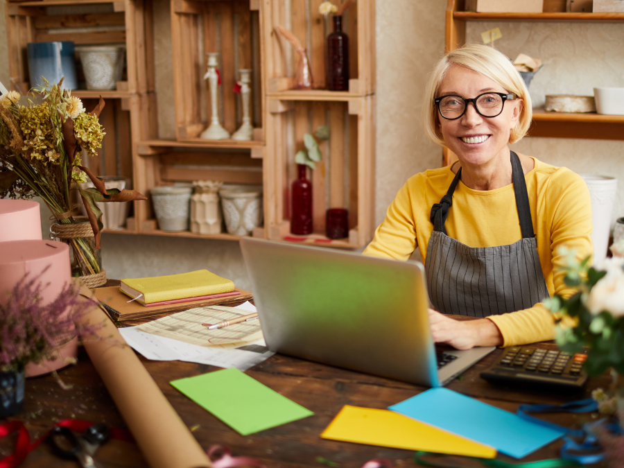 A woman in an apron sitting at a desk using a laptop