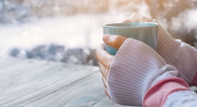 43296692 - side view of female hand holding hot cup of coffee in winter