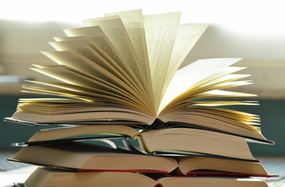 Close-up of several open books stacked together with pages fanned open