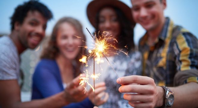 four people hold lit sparklers to the foreground of the camera