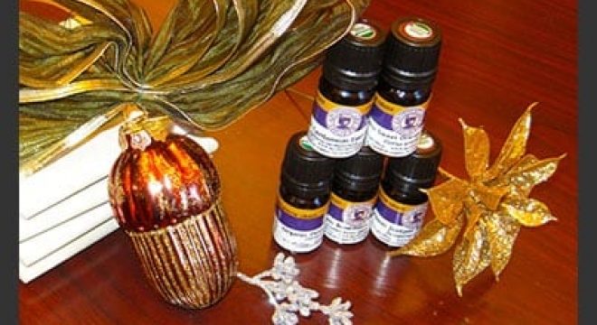 bottles of aromatherapy scents are stacked up next to gold and sparkly holiday decor