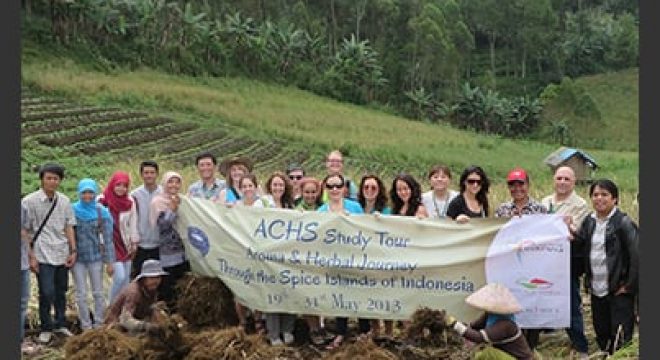 a group of people hold a fabric sign in a field in indonesia celebrating a ACHS study tour