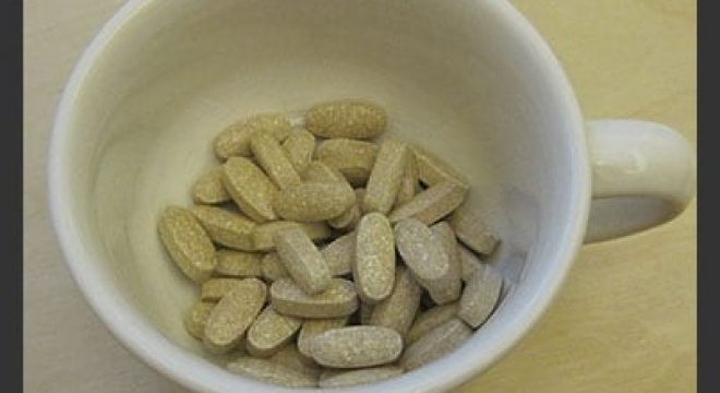 shot of a white mug from above, the mug is holding a few dozen small brown pills speckled with white