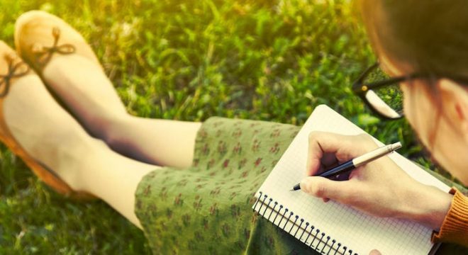 46674968 - girl with pen writing on notebook on grass outside